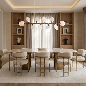 Lyla linear chandelier above an oval marble table with boucle dining chairs and wood shelving