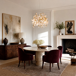 A branching metal chandelier finished in warm brass featuring clusters of raw rose quartz crystals.