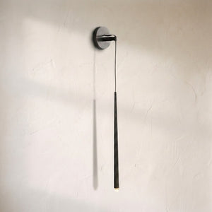 Aurelin grand sconce, slim tapered bronze tube suspended on a cord from a round wall plate