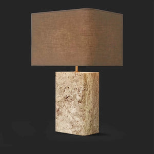 Natural travertine base with copper accents and fabric shade glowing warm