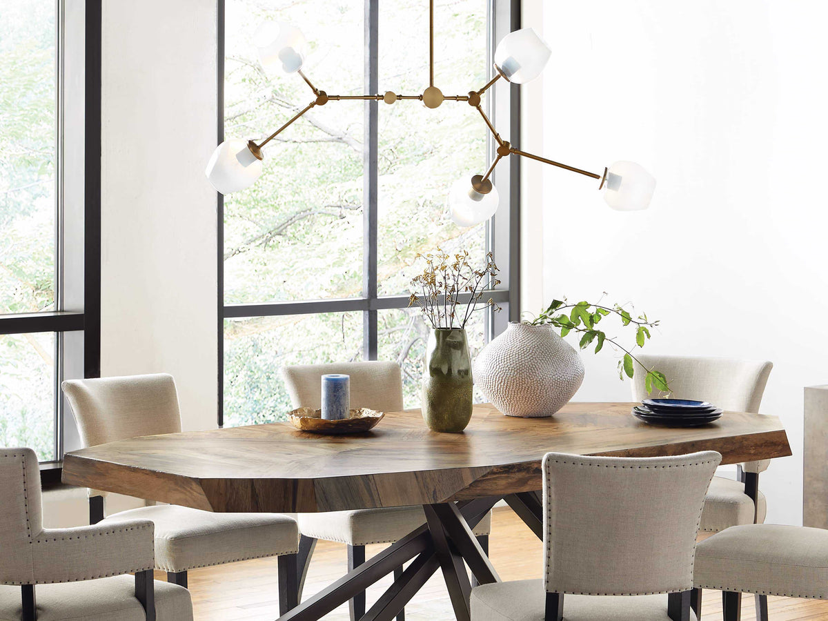 Brass chandelier over a round dining table by a tall window