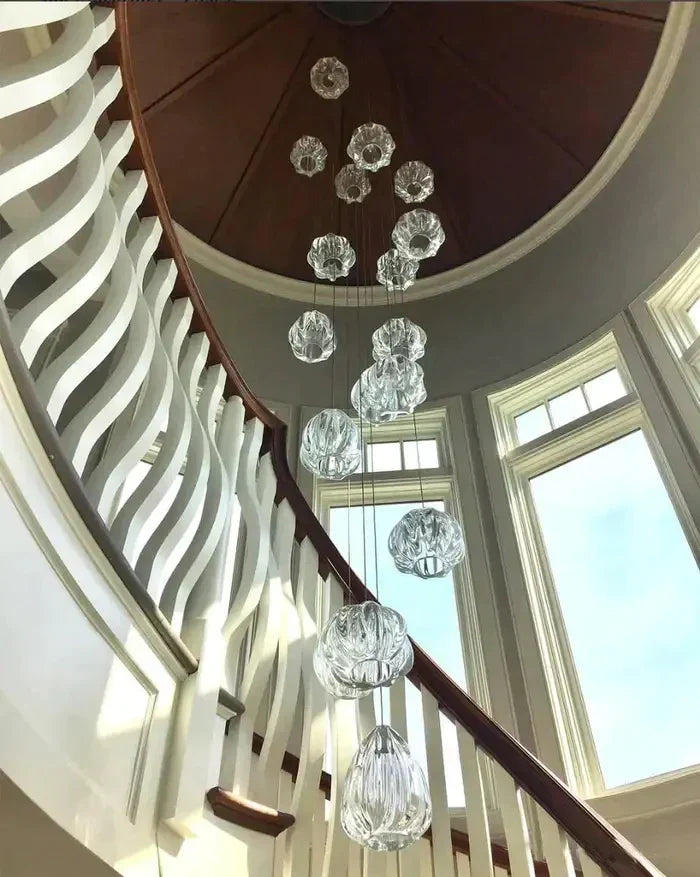 Crystal glass teardrop chandelier cascading down a curved staircase rotunda