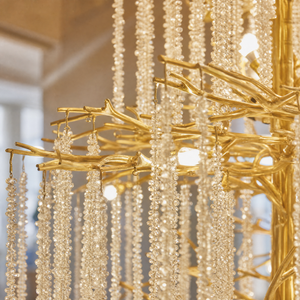 A large, multi-tiered chandelier with a gold branch-like frame and long strands of cascading crystal droplets.