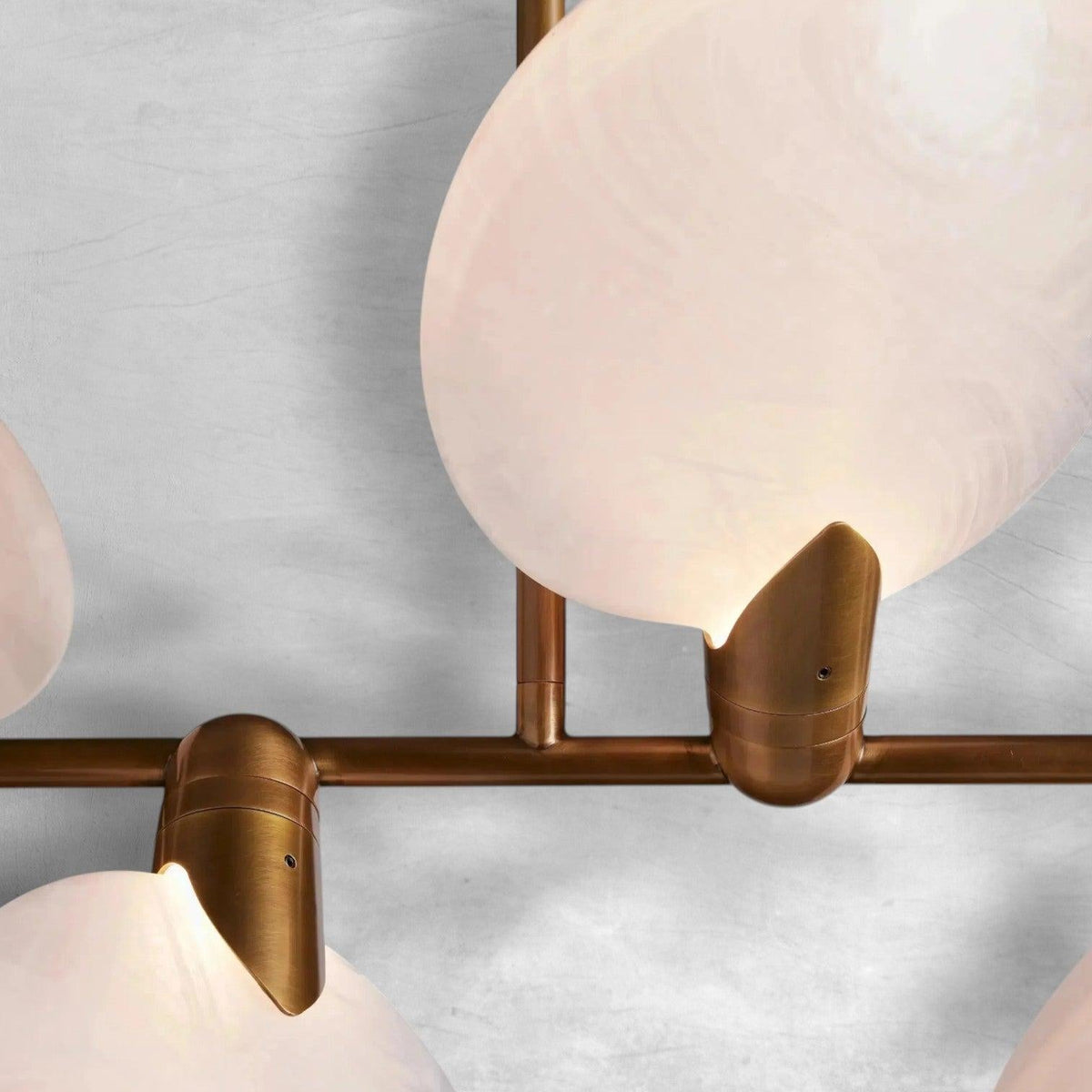 Close-up of Lyla chandelier aged brass fittings holding an alabaster petal shade