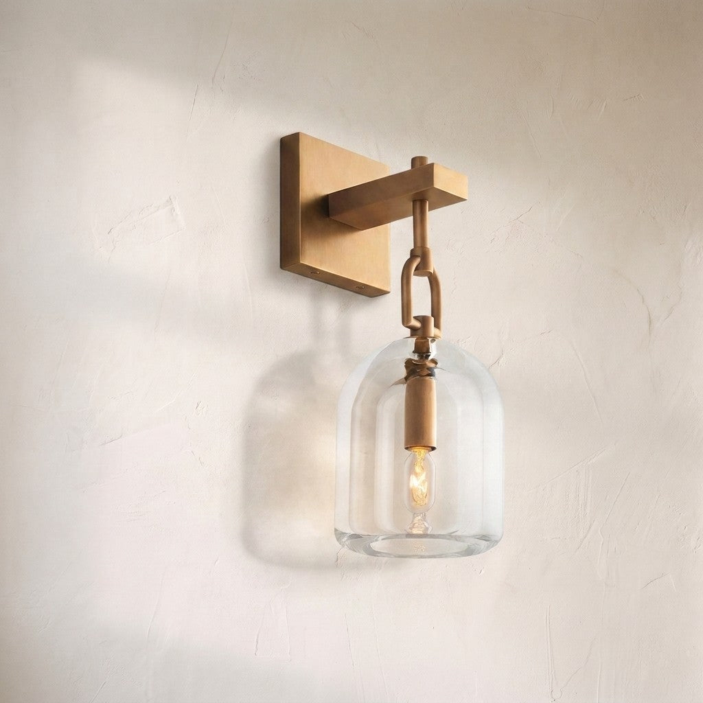 Borealis cloche sconce, clear glass cloche hung from an antique brass arm and square backplate