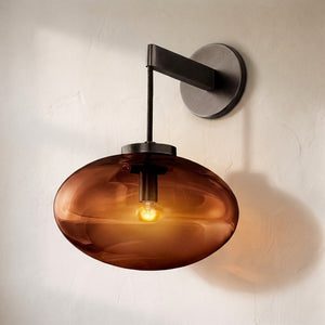 Coraline glass wall sconce, wide amber ellipsoid shade on a bronze arm and round backplate