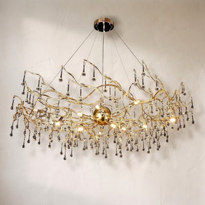 Dawn Livio chandelier, branching brass arms hung with clear crystal teardrops in a wide oval
