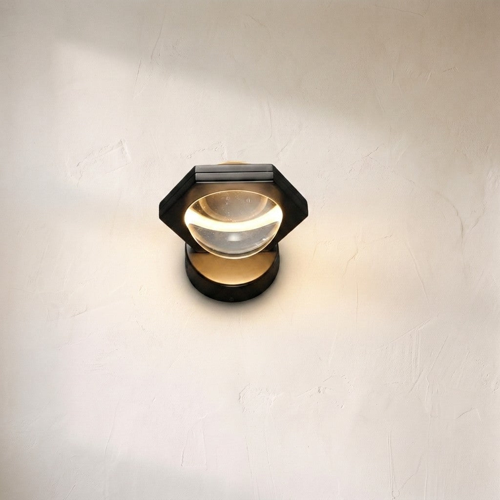 Eldric wall sconce on a plaster wall, black hexagonal frame around a clear glass lens with a warm LED halo