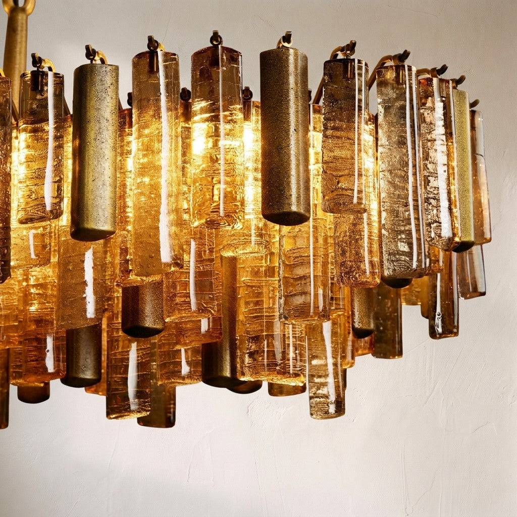 Close-up of the Neve chandelier's amber textured glass batons and brushed metal tubes