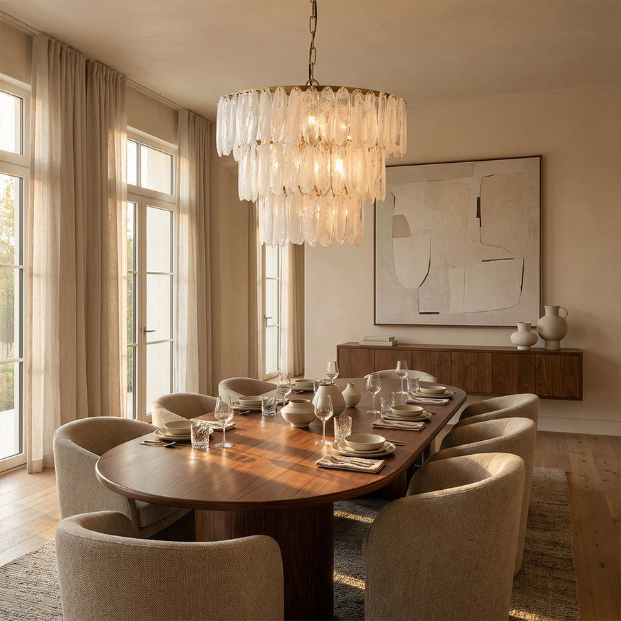 Tiered frosted glass petal chandelier above an oval walnut dining table in a sunlit dining room