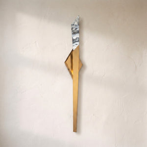 Solitude LED wall light on a plaster wall, tapered brass body rising to a faceted crystal tip